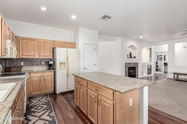 kitchen with a tile fireplace, ceiling fan, white appliances, decorative backsplash, and a kitchen island