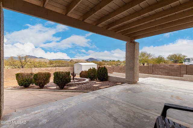 view of patio with a mountain view and a storage shed