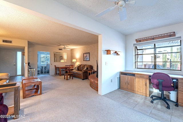 home office with built in desk, a textured ceiling, ceiling fan, and light colored carpet