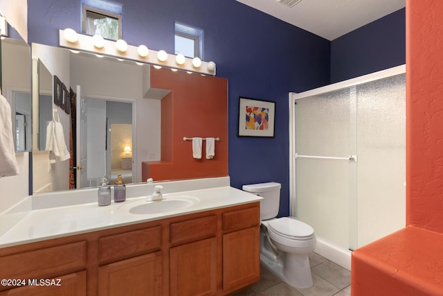 bathroom featuring tile patterned floors, vanity, toilet, and a shower with door