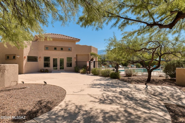 back of property with a patio area, a fenced in pool, and french doors