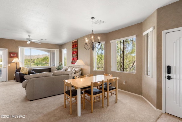 carpeted dining room with ceiling fan with notable chandelier and a healthy amount of sunlight