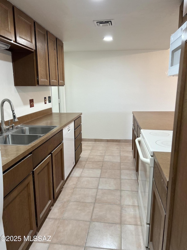 kitchen featuring dark brown cabinets, white appliances, and sink