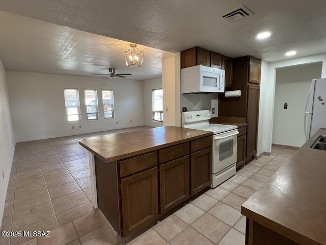 kitchen with ceiling fan with notable chandelier, a healthy amount of sunlight, white appliances, and light tile patterned floors