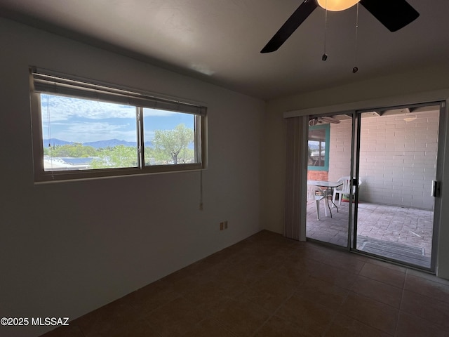 spare room with a mountain view, tile patterned flooring, and ceiling fan