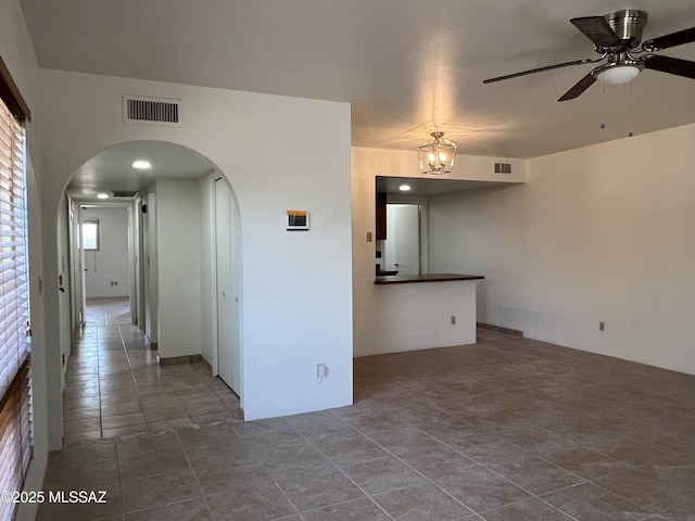 unfurnished room with tile patterned flooring and ceiling fan with notable chandelier