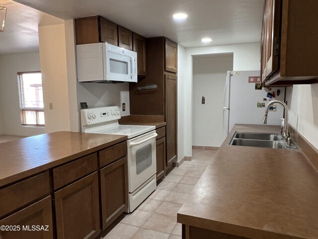 kitchen featuring dark brown cabinetry, sink, and white appliances