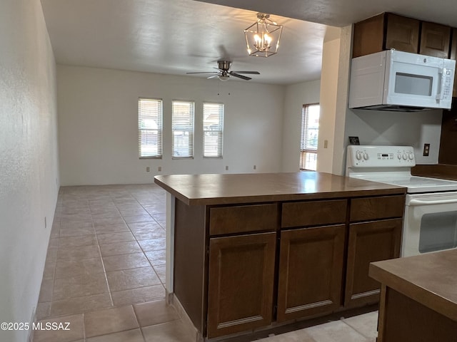 kitchen featuring dark brown cabinets, ceiling fan with notable chandelier, white appliances, light tile patterned floors, and pendant lighting