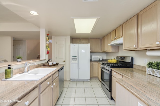 kitchen with sink, light tile patterned floors, light brown cabinets, and appliances with stainless steel finishes