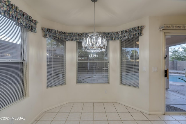 unfurnished dining area featuring light tile patterned floors and an inviting chandelier