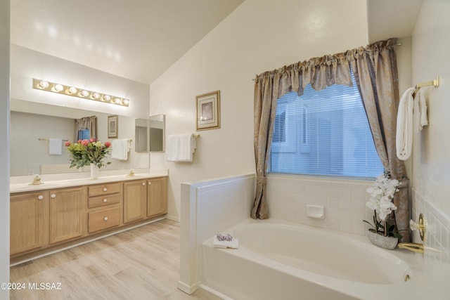 bathroom featuring a bathing tub, hardwood / wood-style floors, vanity, and lofted ceiling