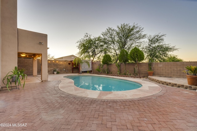 pool at dusk featuring a patio area