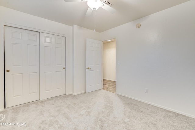 unfurnished bedroom featuring ceiling fan, light colored carpet, and a closet