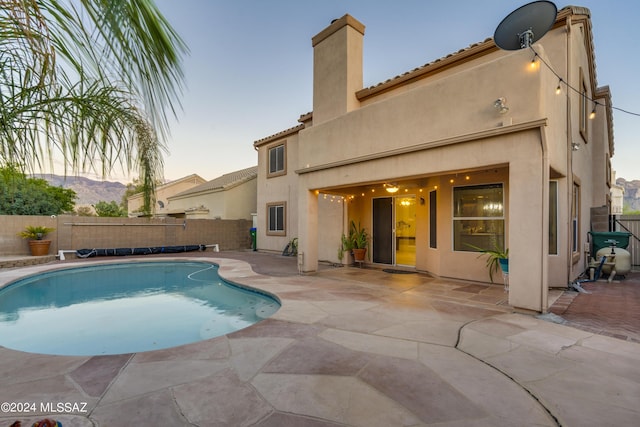 pool at dusk featuring a mountain view and a patio area