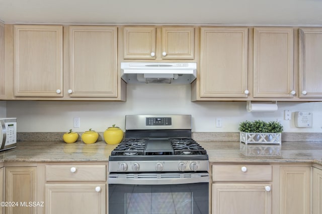 kitchen featuring light stone countertops, light brown cabinets, and stainless steel gas range oven