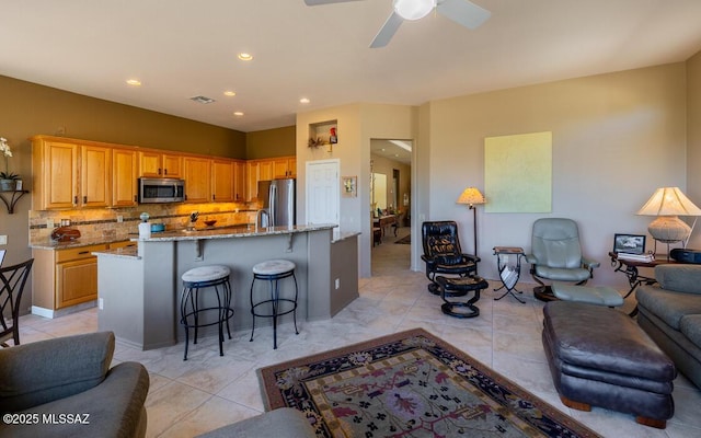 kitchen featuring a breakfast bar area, light stone countertops, tasteful backsplash, and appliances with stainless steel finishes