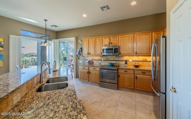 kitchen with decorative backsplash, dark stone counters, stainless steel appliances, sink, and hanging light fixtures