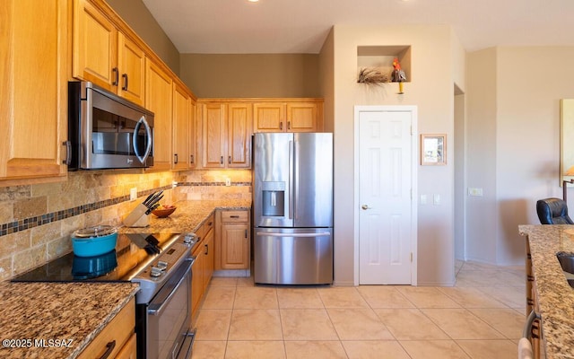 kitchen with backsplash, light stone countertops, light tile patterned floors, and appliances with stainless steel finishes