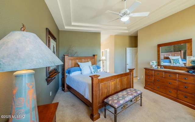 carpeted bedroom with ceiling fan and a raised ceiling