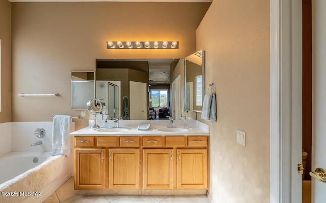 bathroom with a washtub, vanity, and tile patterned floors