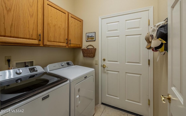 laundry room featuring cabinets, light tile patterned floors, and washing machine and dryer