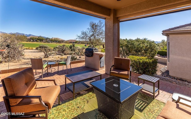 view of patio / terrace with a mountain view, an outdoor hangout area, and an outdoor kitchen