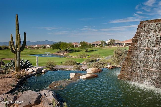 view of property's community with a water and mountain view and a lawn