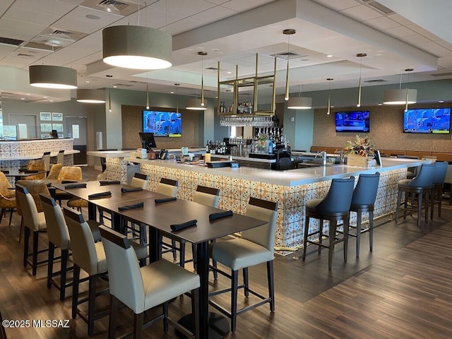 interior space featuring pendant lighting, dark hardwood / wood-style floors, and a drop ceiling