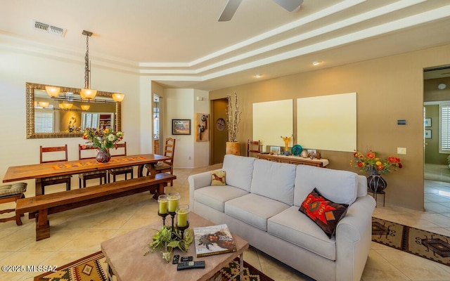 living room with ceiling fan, light tile patterned flooring, and a raised ceiling