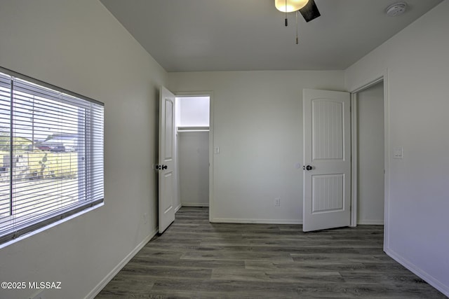 unfurnished bedroom with ceiling fan, dark hardwood / wood-style floors, a spacious closet, and a closet