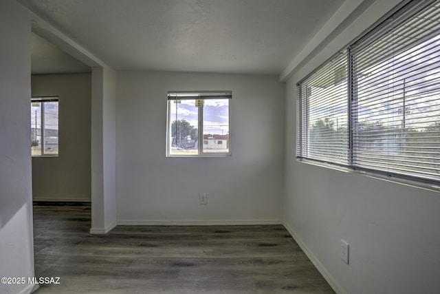 unfurnished room featuring dark wood-type flooring and a healthy amount of sunlight