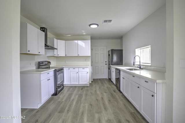 kitchen featuring sink, wall chimney range hood, black appliances, light hardwood / wood-style flooring, and white cabinets