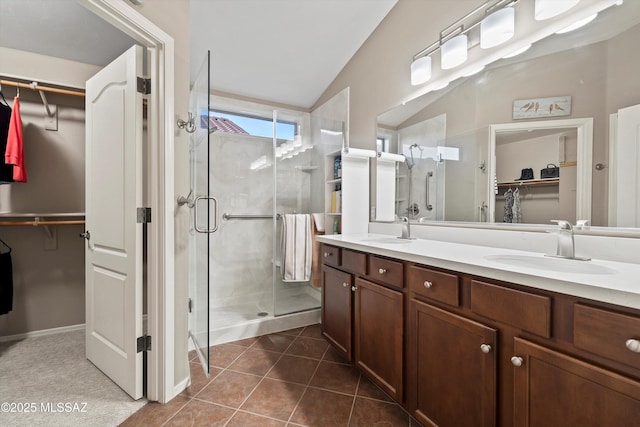 bathroom with a shower with door, vanity, lofted ceiling, and tile patterned flooring