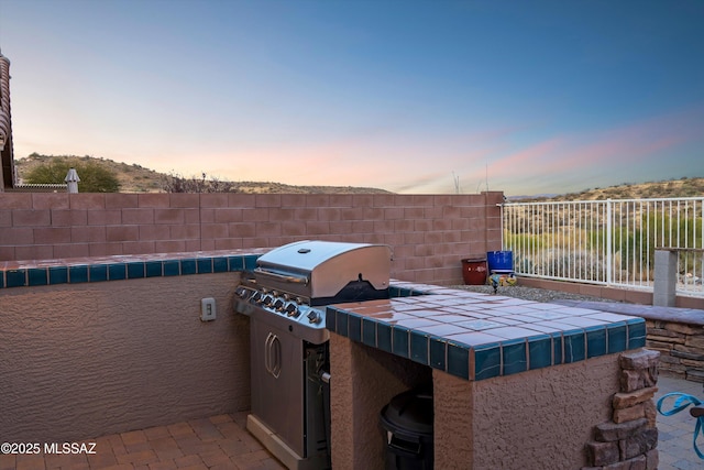 patio terrace at dusk featuring a grill and area for grilling