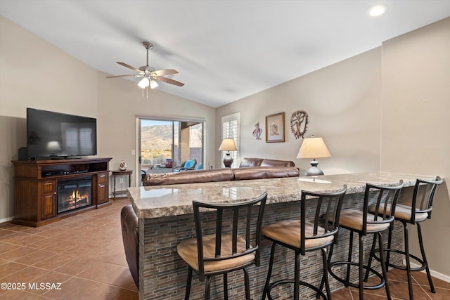 interior space featuring ceiling fan, light stone countertops, lofted ceiling, and light tile patterned flooring