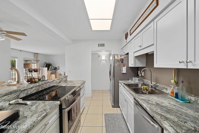 kitchen with ceiling fan, sink, light tile patterned flooring, white cabinets, and appliances with stainless steel finishes