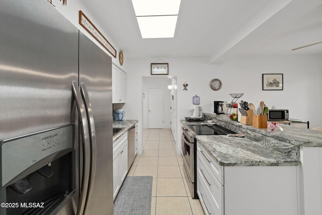 kitchen featuring light tile patterned flooring, light stone countertops, white cabinets, and stainless steel appliances