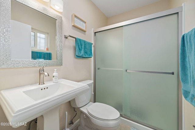 bathroom with toilet, a shower with door, and sink