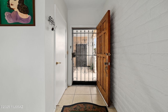 doorway to outside featuring light tile patterned floors and brick wall