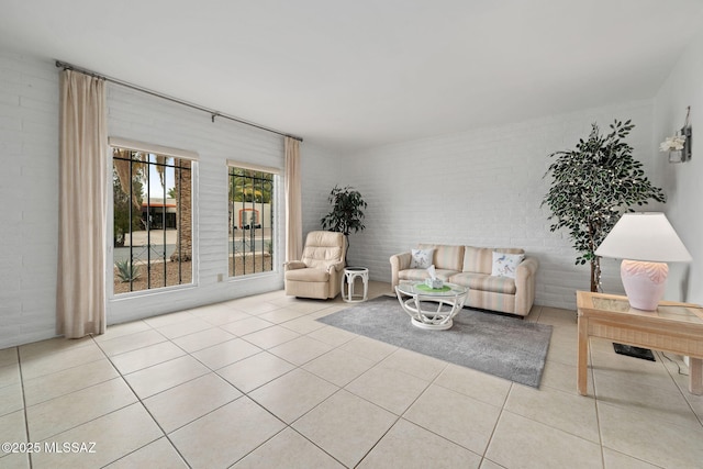 living room featuring light tile patterned flooring and brick wall