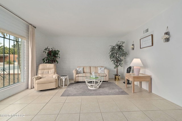 living room featuring brick wall and light tile patterned flooring