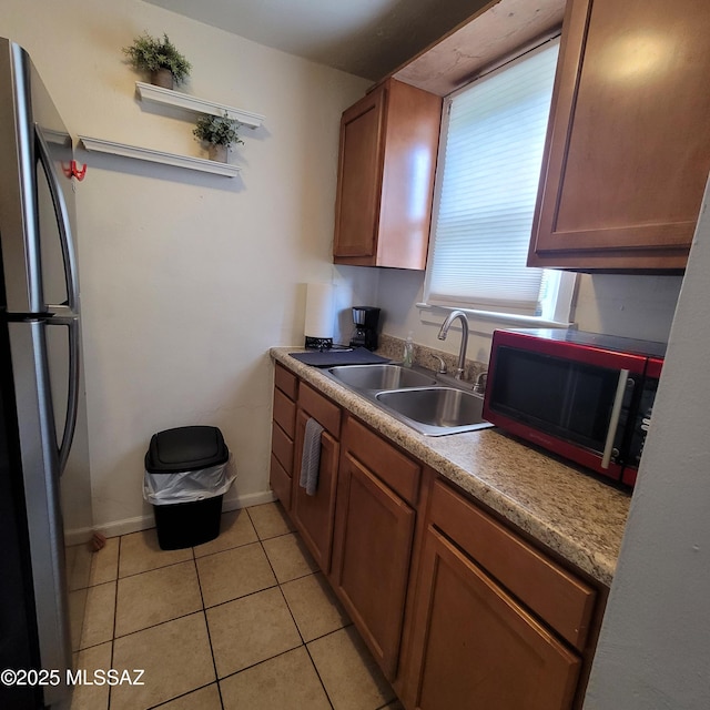 kitchen featuring stainless steel fridge, sink, and light tile patterned floors