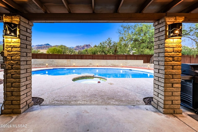 view of swimming pool featuring a mountain view, an in ground hot tub, and a patio