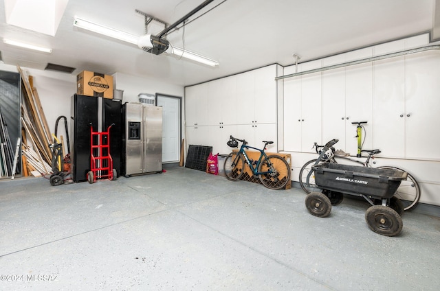 garage with stainless steel fridge with ice dispenser and a garage door opener