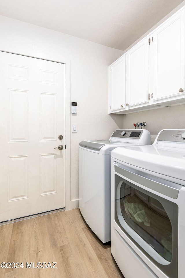 clothes washing area with cabinets, independent washer and dryer, and light hardwood / wood-style flooring