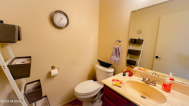 bathroom featuring toilet, a textured wall, and vanity