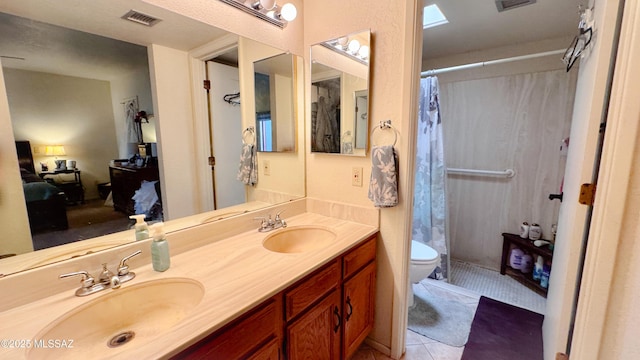 ensuite bathroom with curtained shower, a sink, visible vents, and tile patterned floors