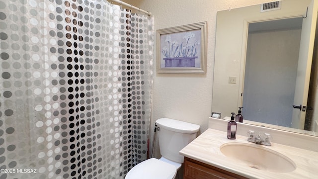 bathroom with visible vents, a textured wall, vanity, and toilet