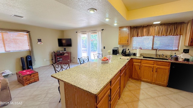 kitchen with brown cabinets, visible vents, a sink, dishwasher, and a peninsula