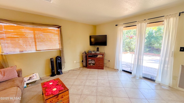 living room with light tile patterned floors, baseboards, and a textured ceiling